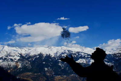 Man throwing snow against mountain during winter