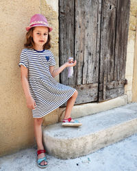 Portrait of young woman standing against wall