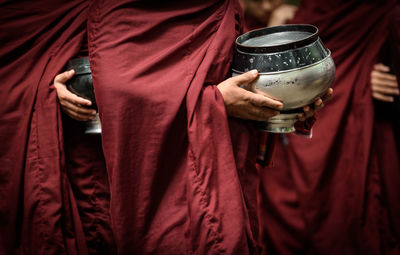 Midsection of men holding religious containers