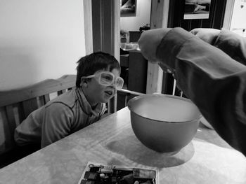Boy holding ice cream in bowl on table