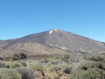 Scenic view of volcanic mountain against clear blue sky