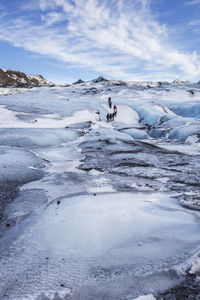 People hiking on glacier against sky