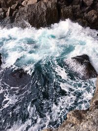 High angle view of waves splashing on rock formation