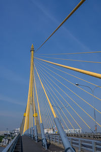 Low angle view of suspension bridge against blue sky