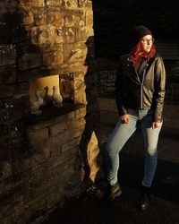 Full length of young woman standing against wall