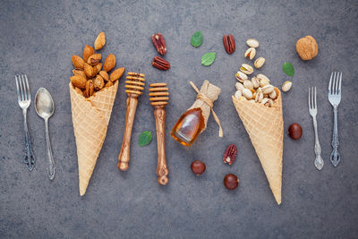 High angle view of ice cream cones with nuts and cutlery on wooden table