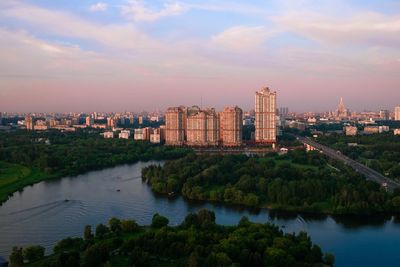 River amidst buildings in city against sky during sunset