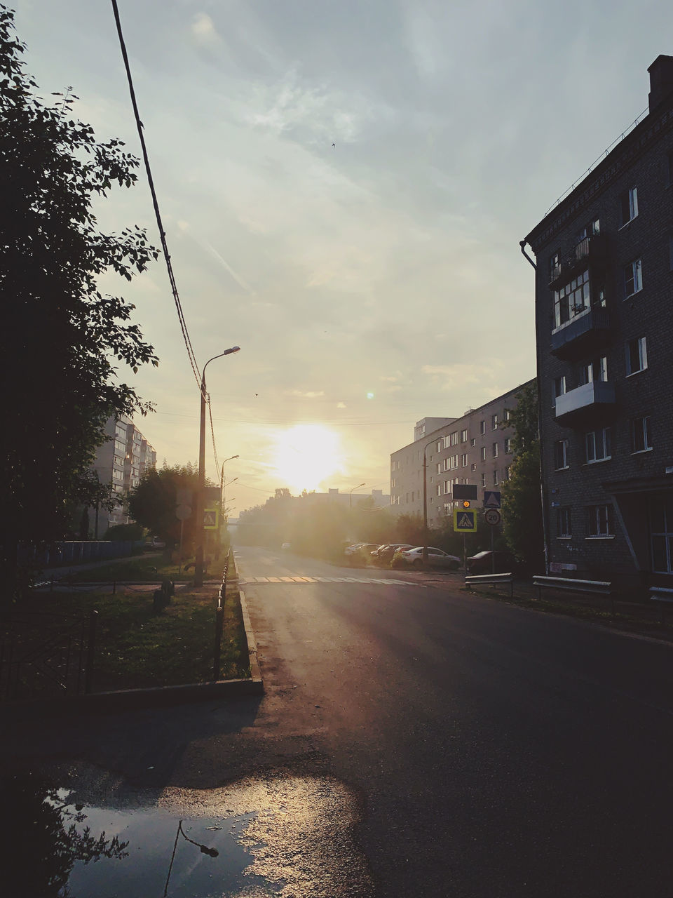 ROAD BY BUILDINGS AGAINST SKY DURING SUNSET