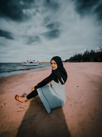 Portrait of young woman on beach against sky