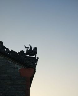 Low angle view of silhouette statue against clear sky