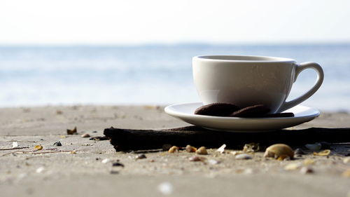 Close-up of coffee cup on beach