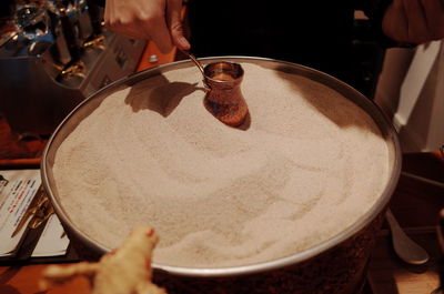 Cropped hand of person holding container over food