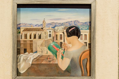 Woman standing by window of building