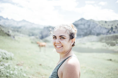 Portrait of young woman standing against mountain