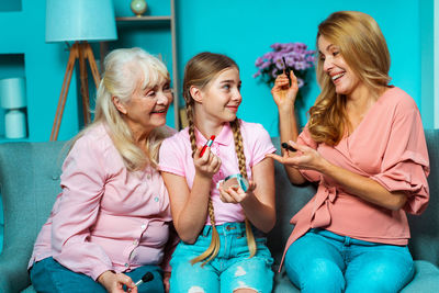 Cute girl applying lipstick with parents