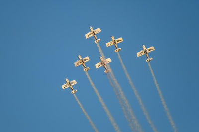 Low angle view of airshow against clear blue sky