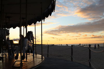 Silhouette people by sea against sky during sunset