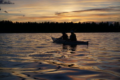 Silhouette of people in lake at sunset