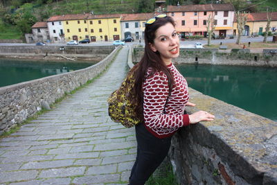 Portrait of beautiful young woman standing by canal