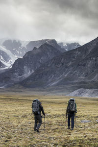 Rear view of two backpackers heading into the mountains.