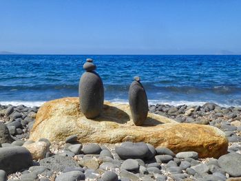 View of pebbles on beach against clear blue sky