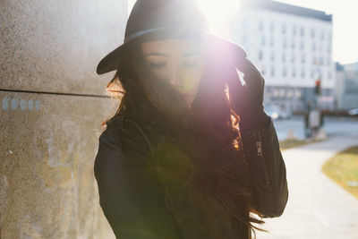 Woman wearing hat by wall in city