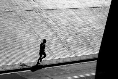 Side view of man jogging on sidewalk