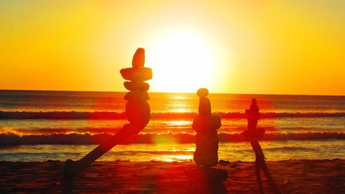 Silhouette people standing at beach during sunset