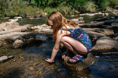 Woman sitting on rock by lake