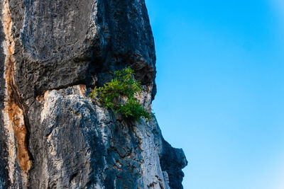 Rock formation by sea against clear blue sky