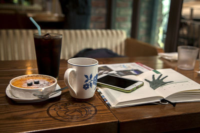 Drinks with creme brulee and mobile phone on table