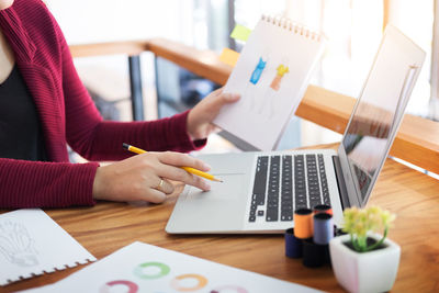 Close-up of woman using laptop on table at home