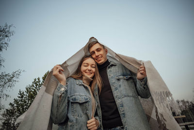 A young couple is covered with a plaid in the form of a house roof. house concept