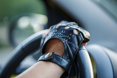 The driver's hands in leather gloves driving a moving car. woman holding