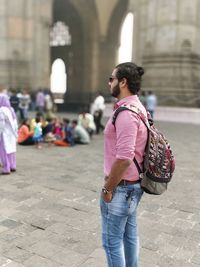 Side view of man with backpack standing against monument