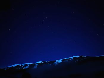 Scenic view of mountains against blue sky at night