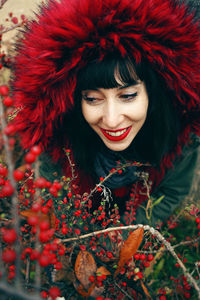 High angle view of woman wearing warm clothing amidst red berries on plants