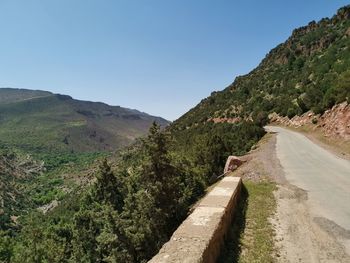 Road leading towards mountains against clear sky