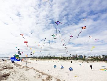 Low angle view of kites flying over beach against sky