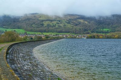 Scenic view of river by mountains against sky