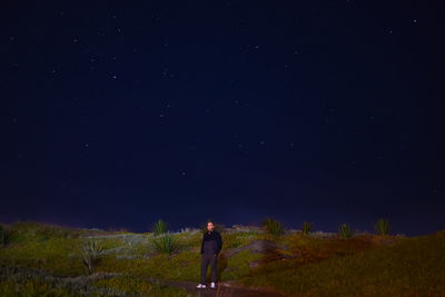 Woman standing on field against sky at night
