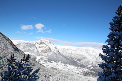 Scenic view of snowcapped mountains against blue sky