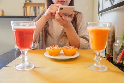 Midsection of woman holding wineglass on table