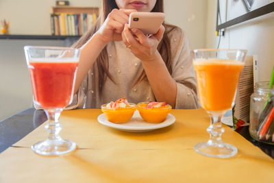Midsection of woman photographing food through mobile phone at home
