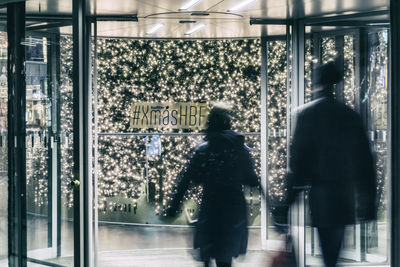 Rear view of men looking through glass window
