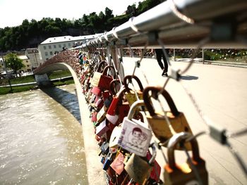 Padlocks on bridge over river in city