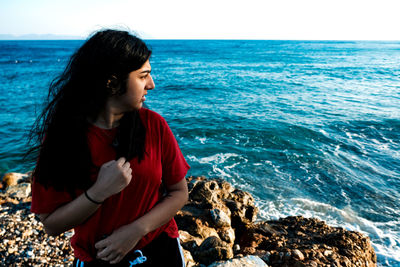 Woman looking at sea shore against sky