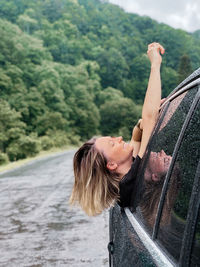 Rear view of woman walking on road against trees