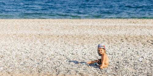 Full length of girl sitting on sand at beach