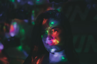 Close-up of thoughtful young woman in illuminated room at night